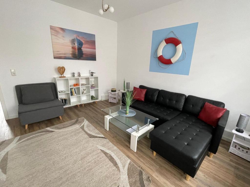 ein Wohnzimmer mit schwarzem Sofa und einem Sessel in der Unterkunft Brigg in Emden