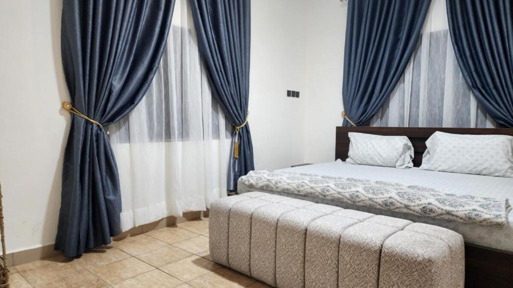 a bedroom with a bed with blue curtains and a couch at LaCasa Abuja in Abuja