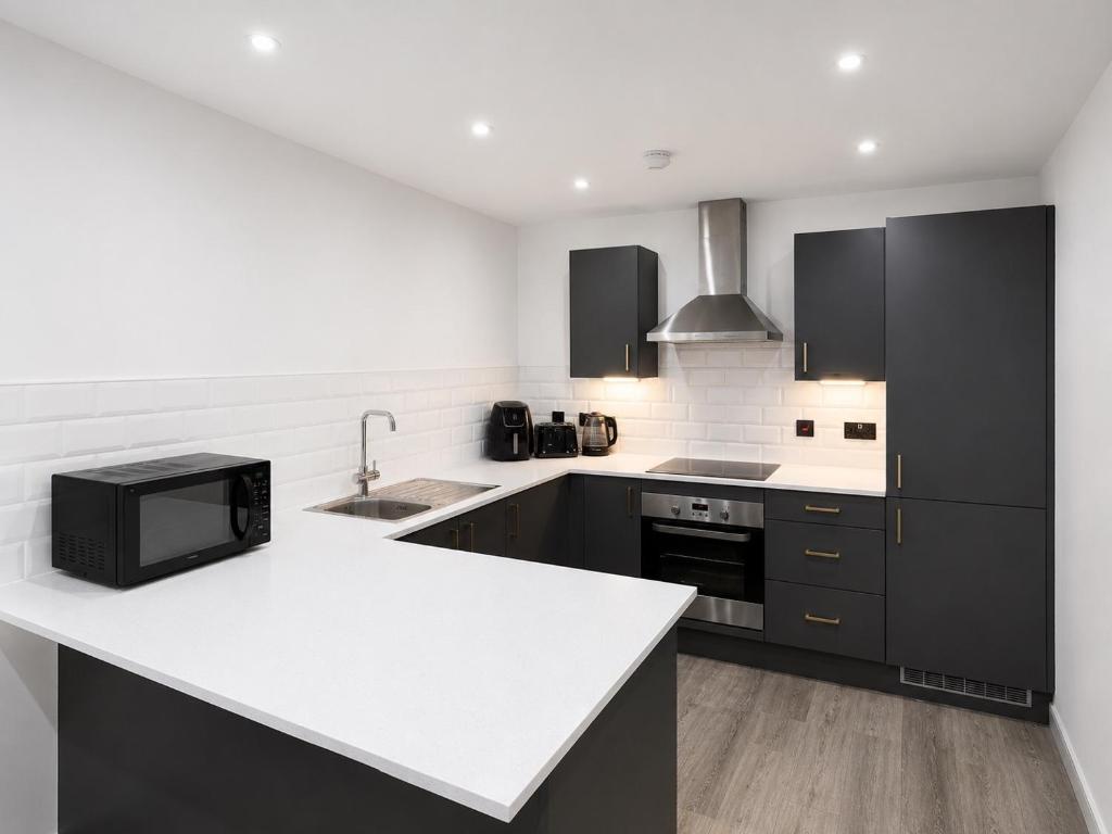 a kitchen with black cabinets and a white counter top at AS Residences in Preston
