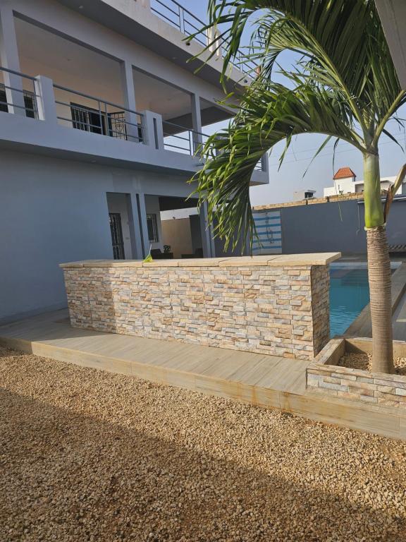 a retaining wall in front of a house with a palm tree at la dorée du Sénégal appartement rez-de-chaussée in Somone
