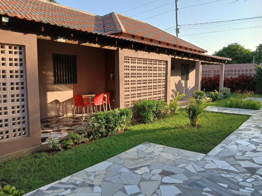 a house with a patio and red chairs in the yard at Casa T2 in Matola