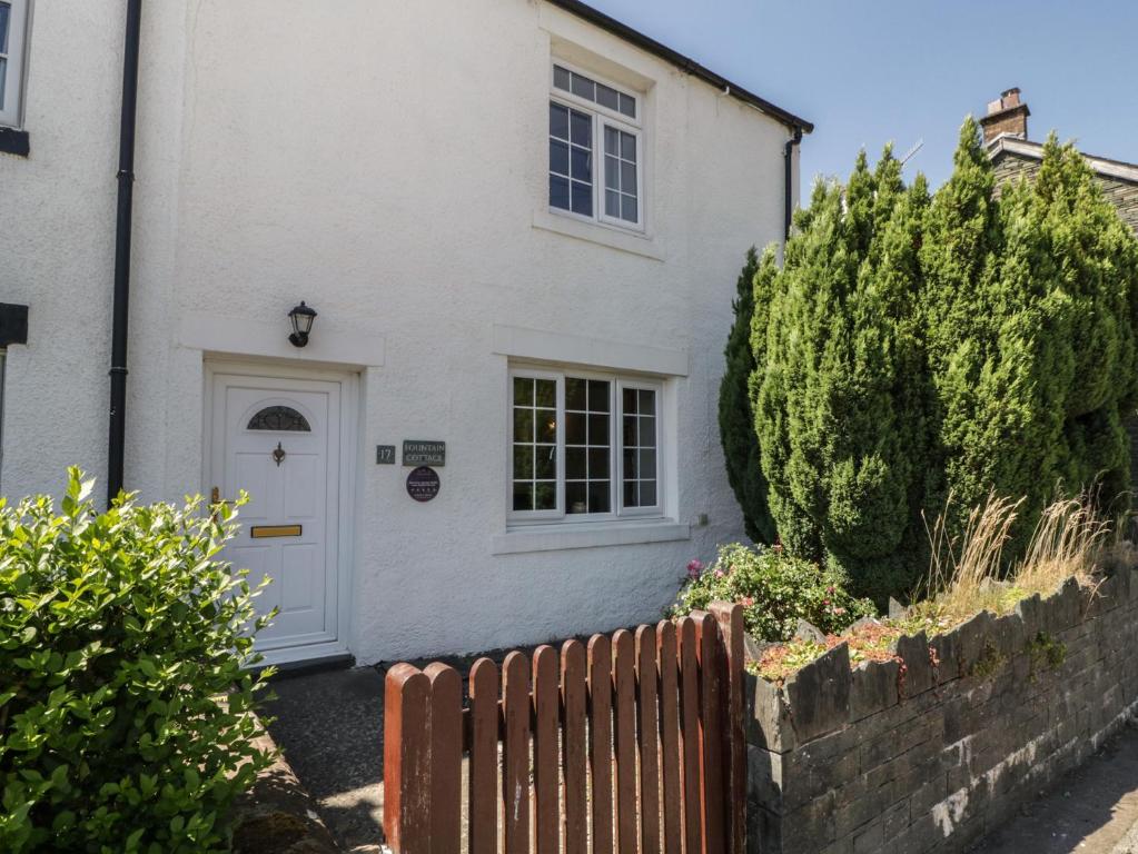 a white house with a white door and a fence at Fountain Cottage in Keswick