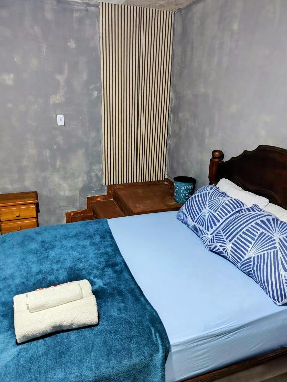 a bedroom with a bed with a blue comforter at suíte feliz in Belém