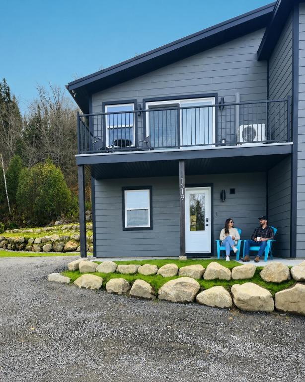 two people sitting on chairs outside of a house at Condo à Mont-Blanc près de tout in Saint-Faustin