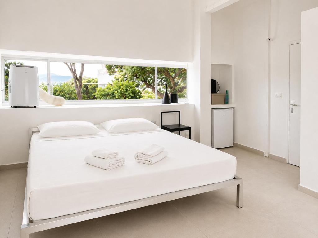 a white bedroom with a large white bed with two towels at ÉLÉGANT STUDIO et PARKING DANS BATIMENT HISTORIQUE in Saint-Tropez
