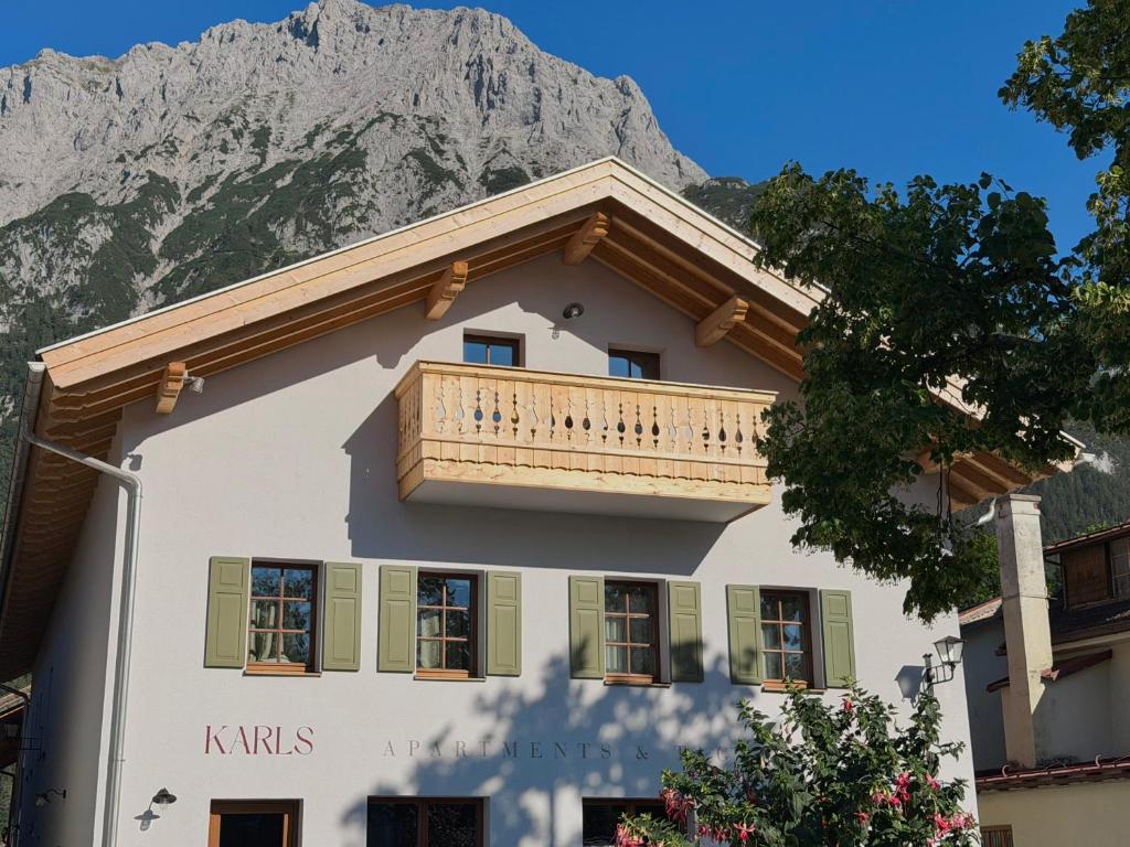 a building with a balcony with a mountain in the background at Karls Mittenwald - Design Apartments mit Alpenblick & Tagesbar im Herzen von Mittenwald in Mittenwald