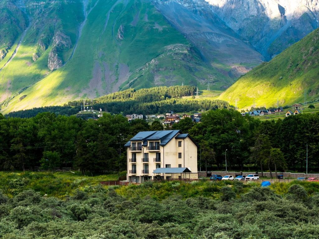 a building with a mountain in the background at Hotel Gold Kazbegi in Kazbegi
