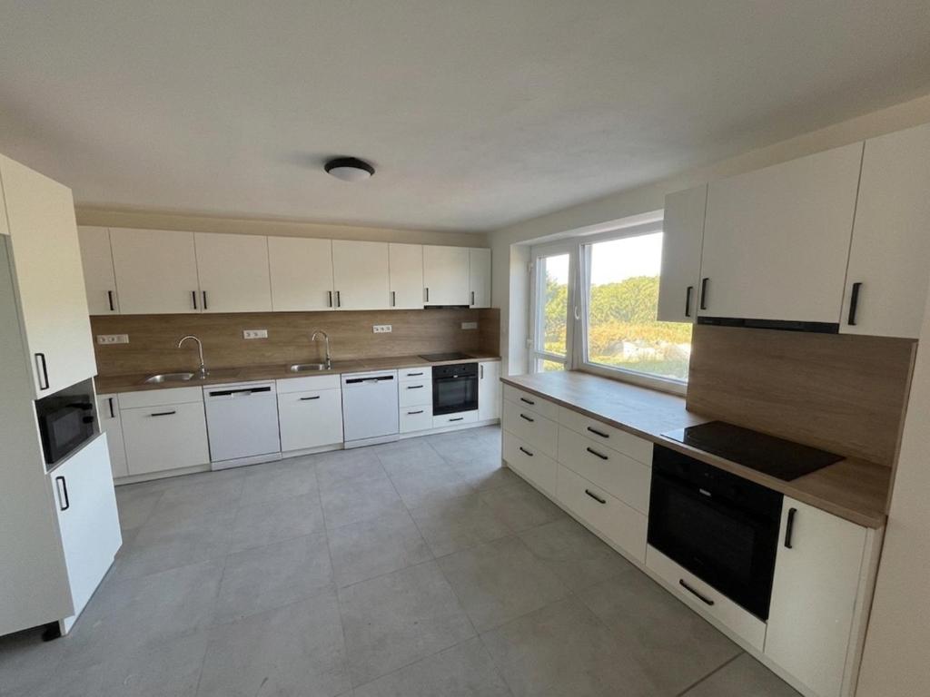 a large kitchen with white cabinets and a window at Hakro Jevisovka in Jevišovka