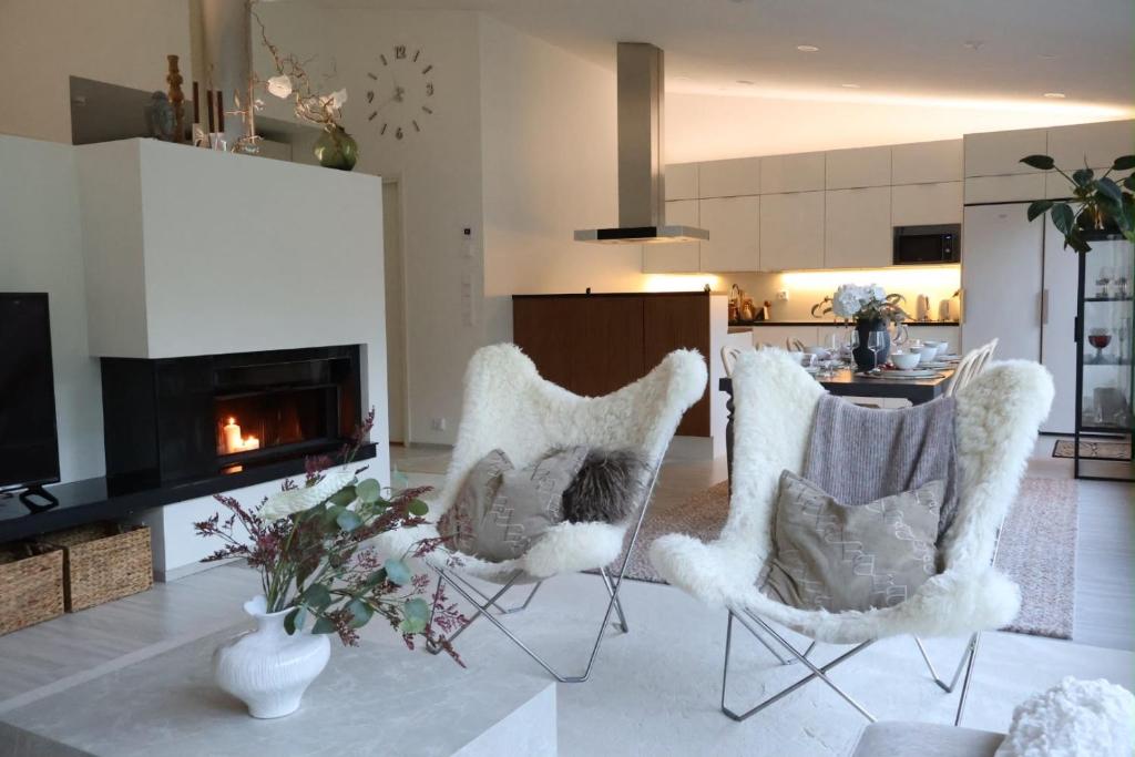 a living room with two chairs and a fireplace at Villa Lydia Lapland - Private Sauna & Aurora View in Rovaniemi