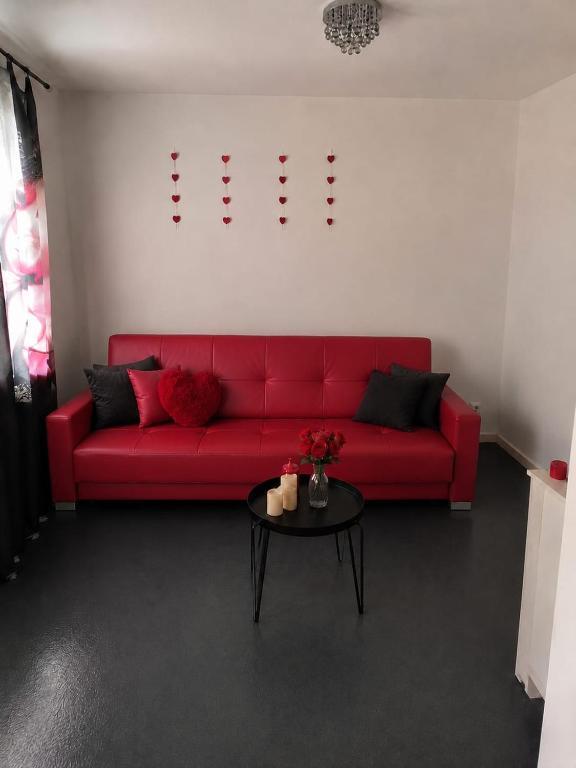 a red couch in a living room with a table at Sercowe Zacisze in Chełmża
