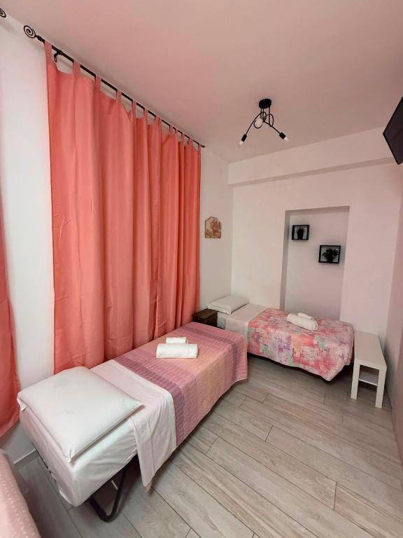 two beds in a room with orange curtains at Villa Santa Chiara in Loreto