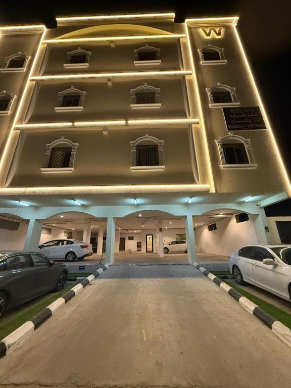 a large building with cars parked in a parking lot at شقق وهل in Dammam