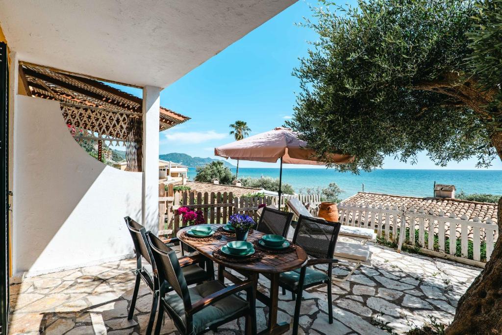 a table with chairs and an umbrella on a patio at Corfu Glyfada Beach Apartment 24 in Glyfada