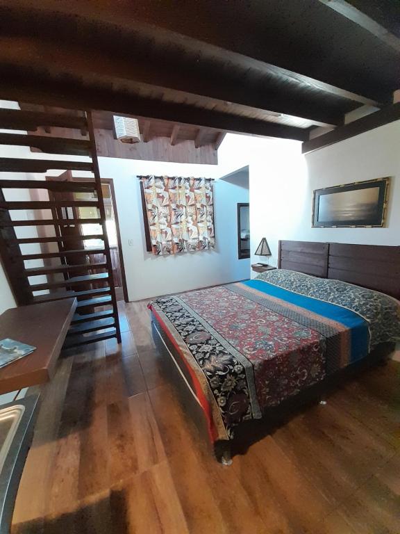 a bedroom with a bed and a wooden floor at Santa Monica Hospedaria in Praia do Rosa