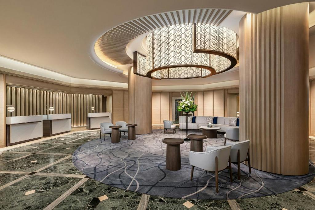 a lobby with tables and chairs and a chandelier at Kobe Marriott Hotel in Kobe