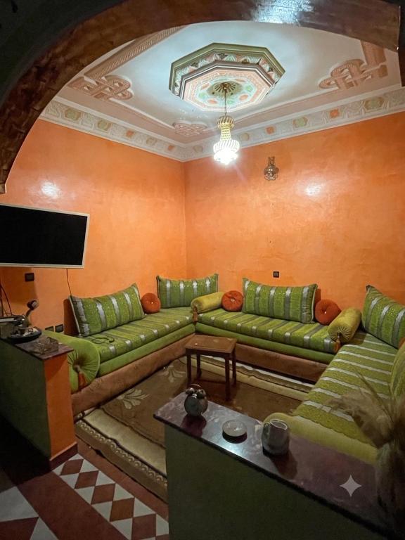 a living room with green couches and a flat screen tv at MEFTAH lkhir hay nour in Safi