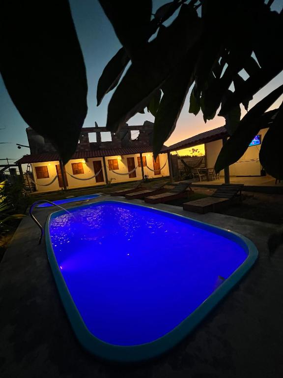 a blue swimming pool in front of a house at Suite Adam 3 em Caraíva com piscina 900m da Vila in Caraíva