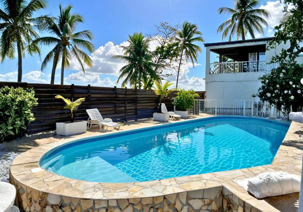 ein Swimmingpool mit Palmen und ein Haus in der Unterkunft Hotel Le Rotabas in Sainte-Anne