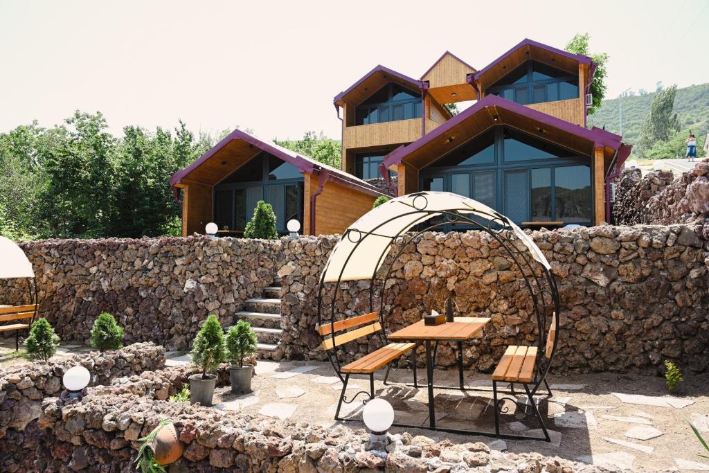 a house with a table and chairs in front of a stone wall at EKA Resort in Goris