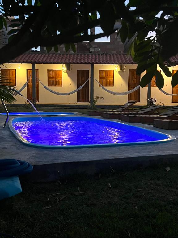 a blue swimming pool in front of a house at Suíte Adam 2 em Caraíva com Piscina 900m da Vila in Caraíva