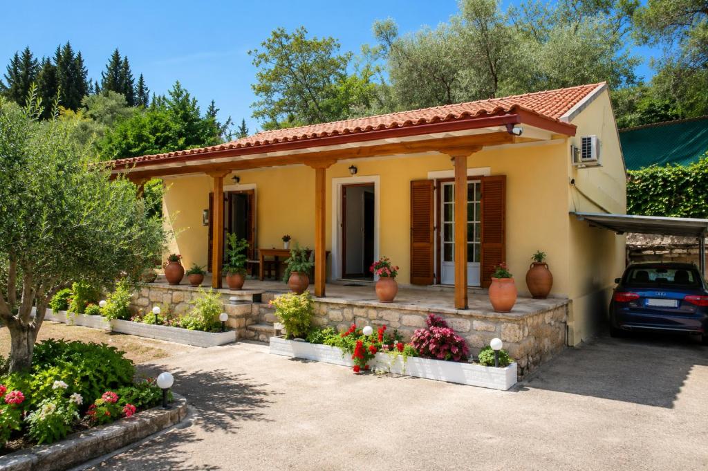 a small yellow house with flowers in front of it at Ozias House in Oziás