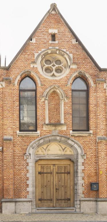 a brick building with a large door and two windows at Unique renovated chapel in Temse
