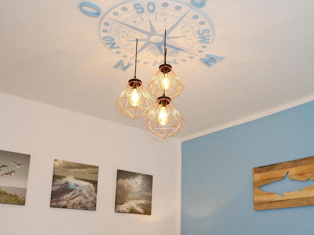 a clock on a ceiling with a chandelier at Fischerhaus Bremerhaven in Bremerhaven