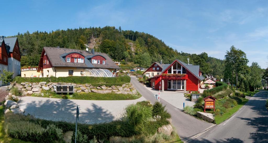 a village with red and white houses and a road at Rodinný resort UKO in Bedřichov