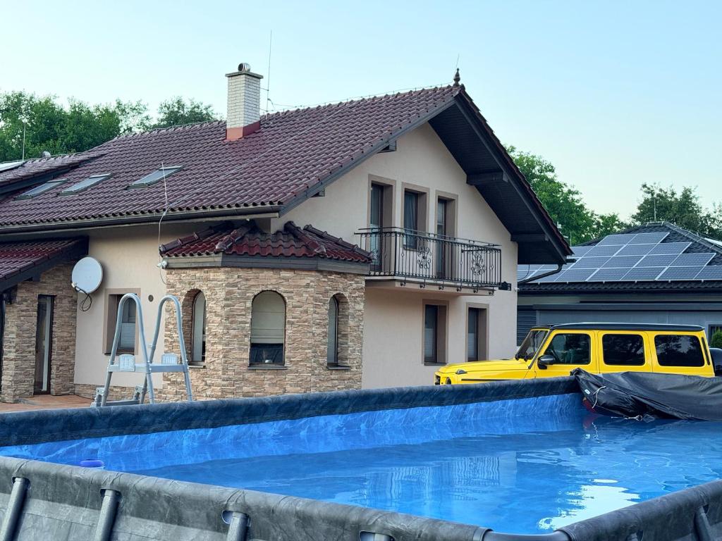 a yellow van parked in front of a house with a swimming pool at Dom v stráni in Poniky