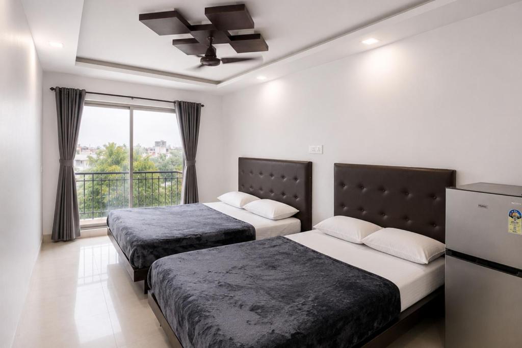 two beds in a room with a window at SAVRAJ Stay Beach Goa in Candolim