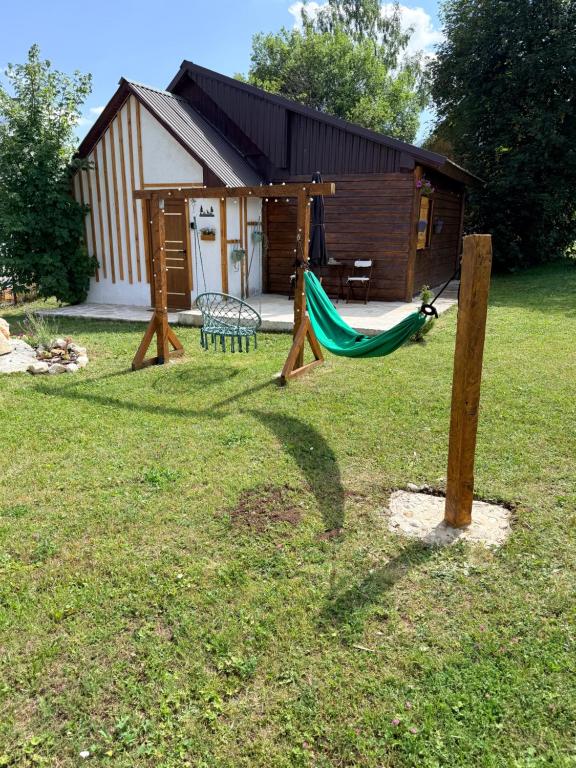 a playground with a hammock in front of a cabin at Wooden house Durmitor in Žabljak