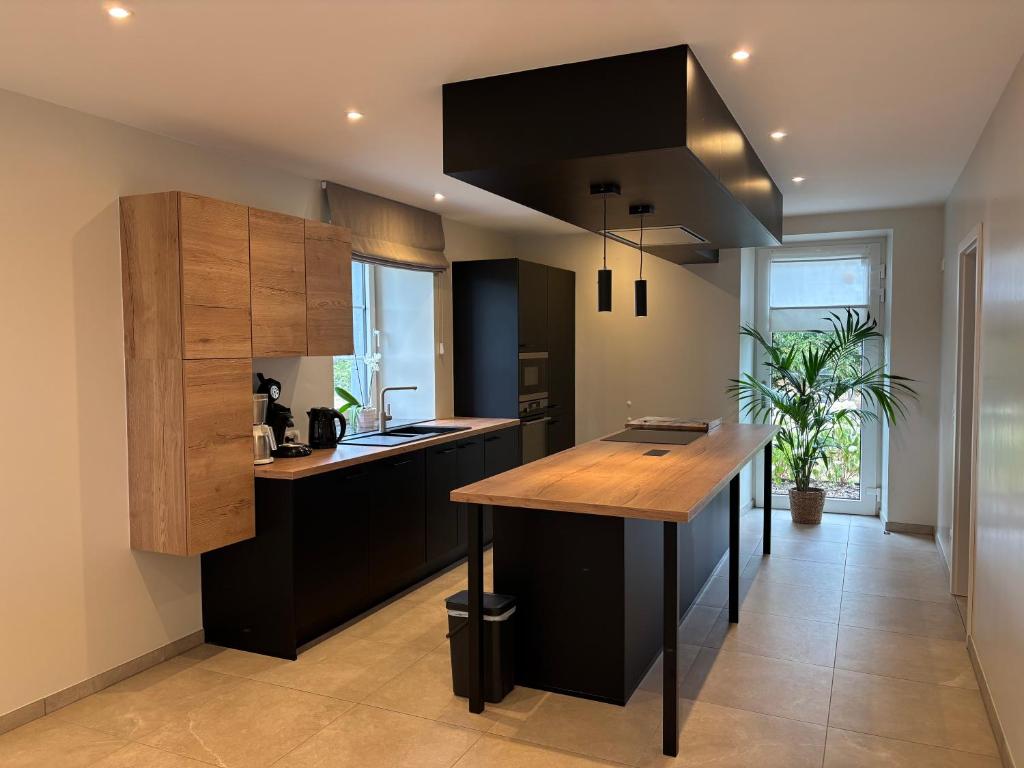 a kitchen with black cabinets and a wooden island at La Petite Reine in Bertrix