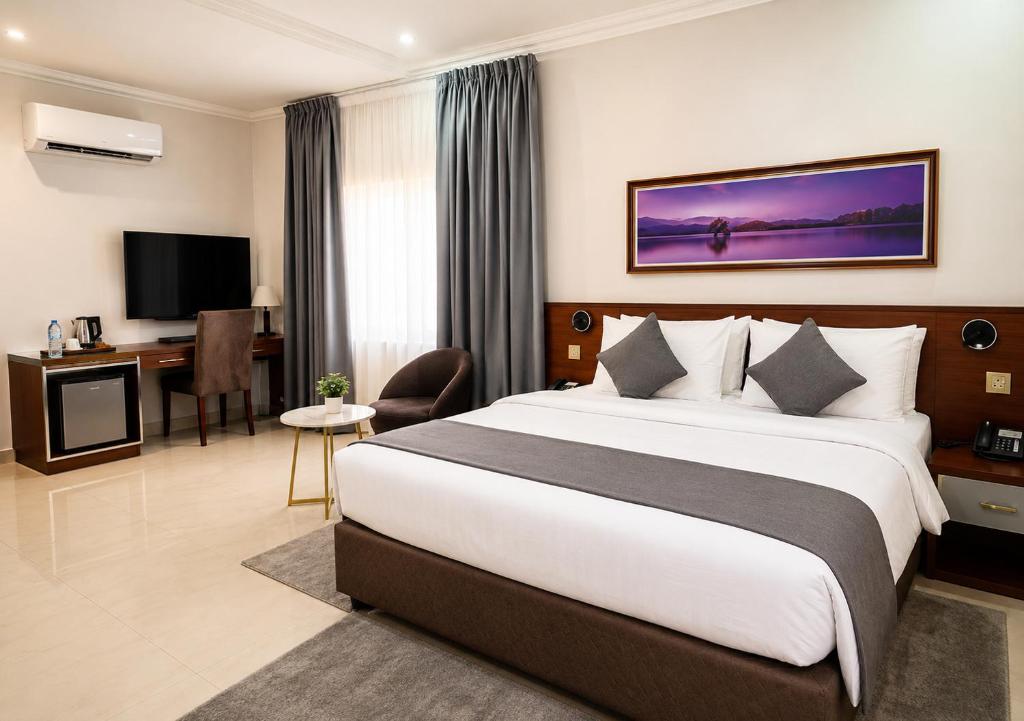 a hotel room with a large bed and a desk at Kaslon Hotel, Garki 2 Abuja in Abuja