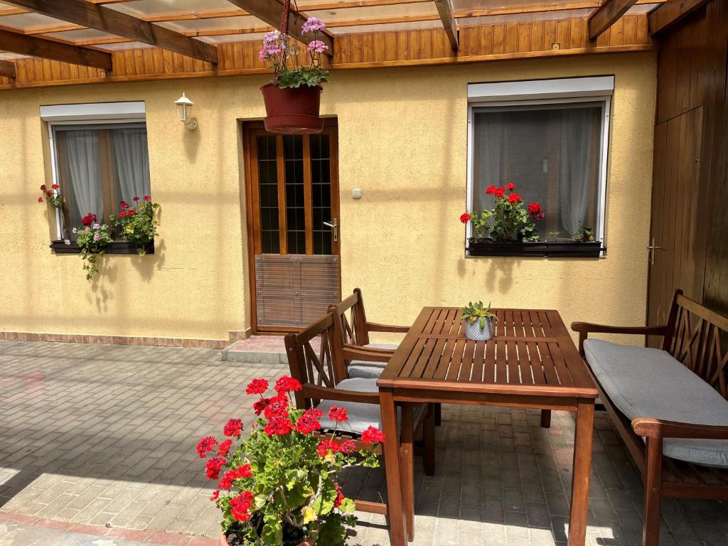 a patio with a wooden table and chairs and flowers at Handó Porta in Szenna