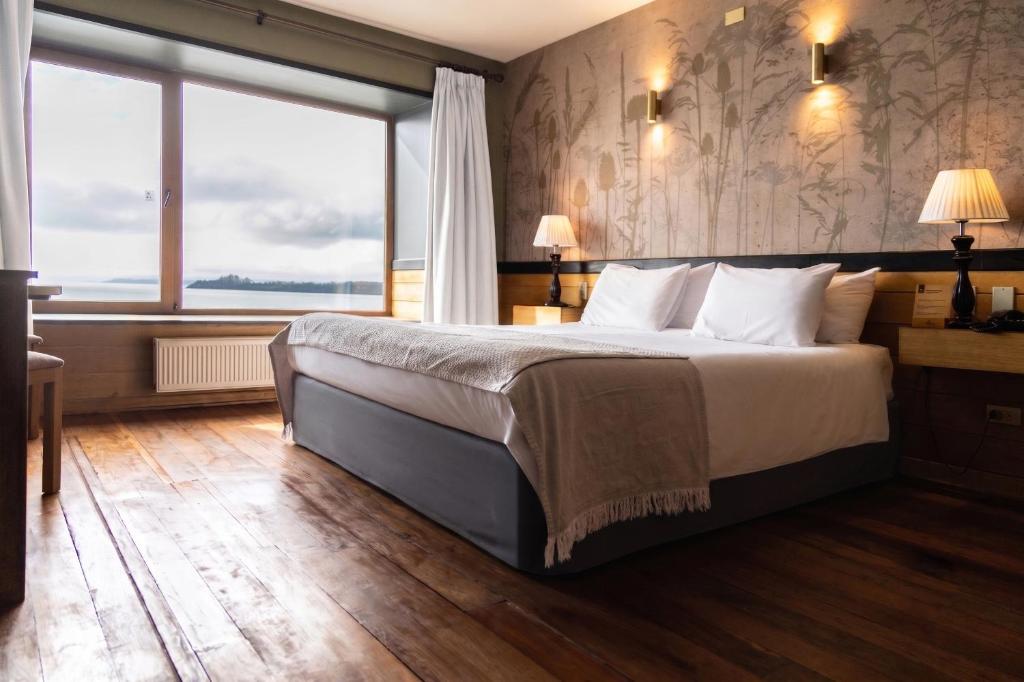 a bedroom with a large bed and a large window at Hotel Bellavista in Puerto Varas