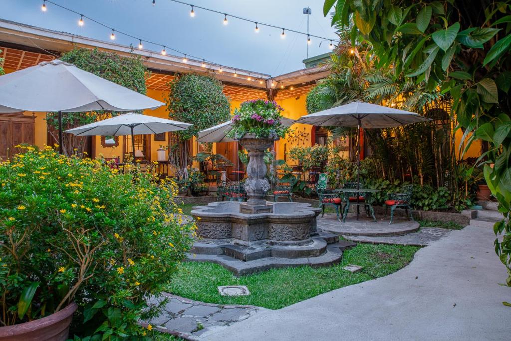 a garden with a fountain with umbrellas and tables and chairs at Hotel Casa Antigua by AHS in Antigua Guatemala