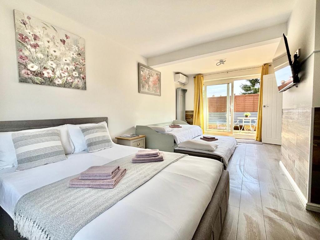 two beds in a room with a window at Gatwick Studio in Horley