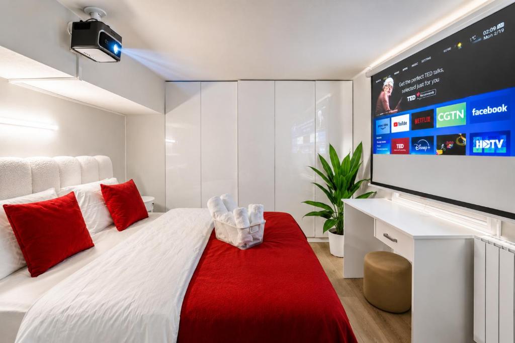 a bedroom with a white bed with red pillows and a flat screen tv at Vake Dream Duplex in Tbilisi City