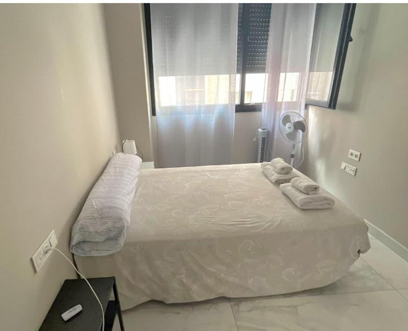 ein weißes Bett in einem Zimmer mit Fenster in der Unterkunft Modern central flat in Ceuta