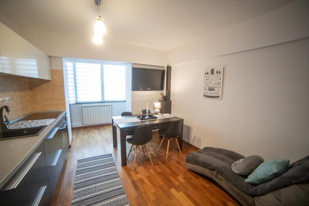 a kitchen and a living room with a table and a couch at M-Buf Center Apartament in Gura Humorului