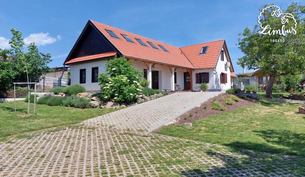 a house with an orange roof and a brick driveway at Limbus Fogadó in Gyöngyöstarján