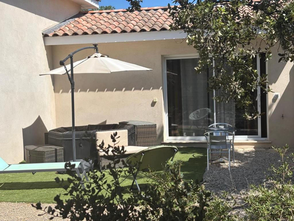 a patio with an umbrella and a table and chairs at Au Petit Bueix in Sillans-la Cascade