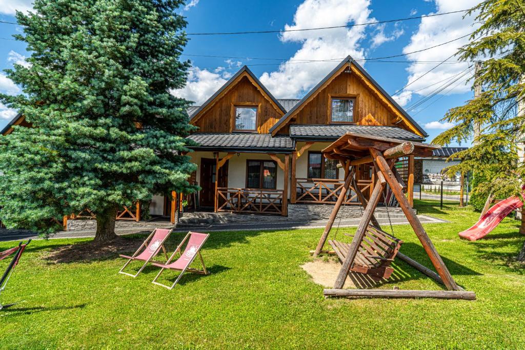 a log home with chairs and a swing at DW KINGA Domki całoroczne 6 os z widokiem na Tatry in Kacwin