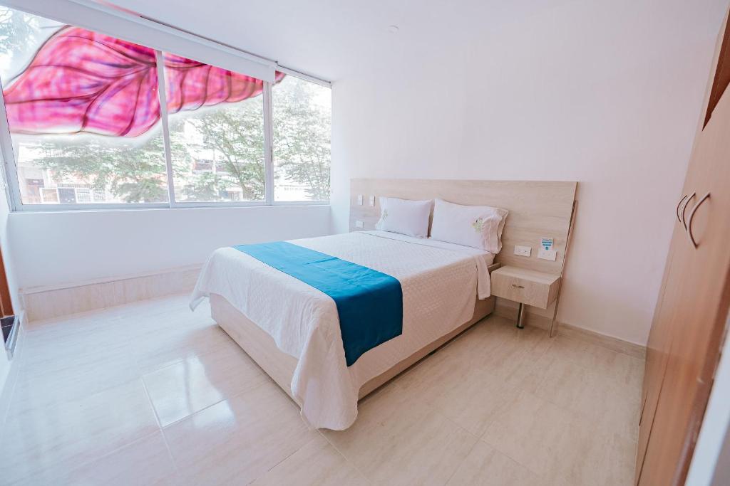 ein weißes Schlafzimmer mit einem Bett und einem Fenster in der Unterkunft Apartamento Edificio Neon Centro in Ibagué