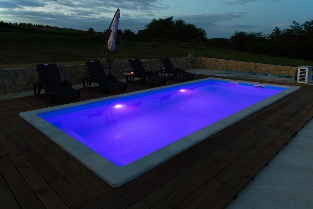 a swimming pool with purple lighting on a deck at Brvnara Staničić sa privatnim bazenom in Arandelovac