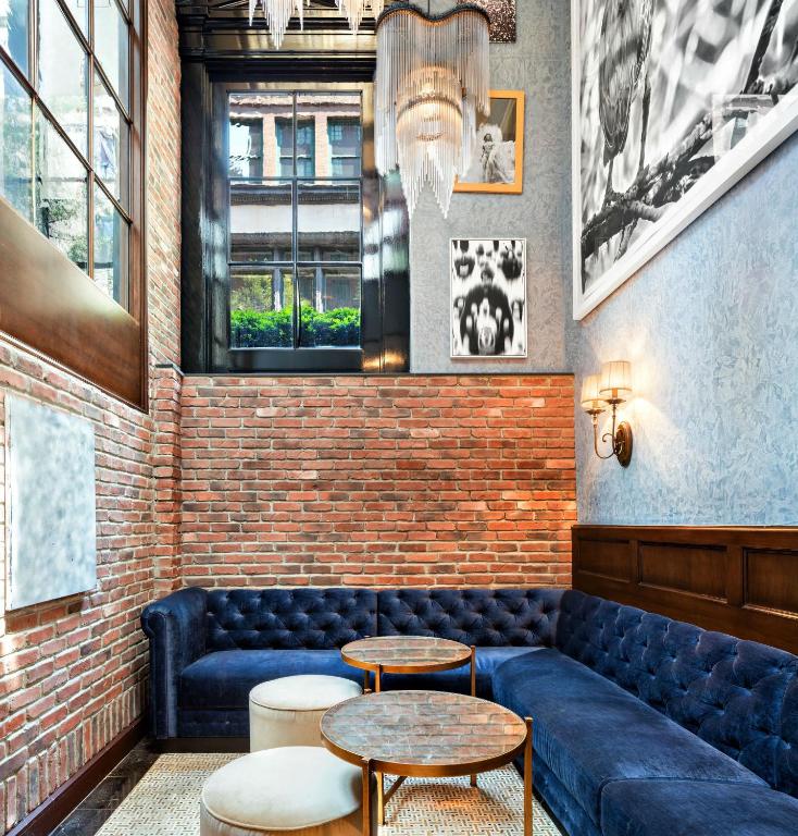 a room with a blue couch and two tables at Walker Hotel Greenwich Village in New York