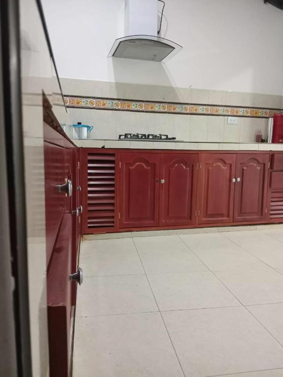 a kitchen with red cabinets and a white tile floor at La Clandestina in Chachagüí