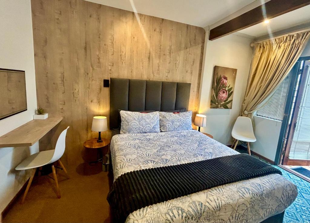 a bedroom with a bed and a table and chairs at Naby-My Stellenbosch Cottage in Stellenbosch