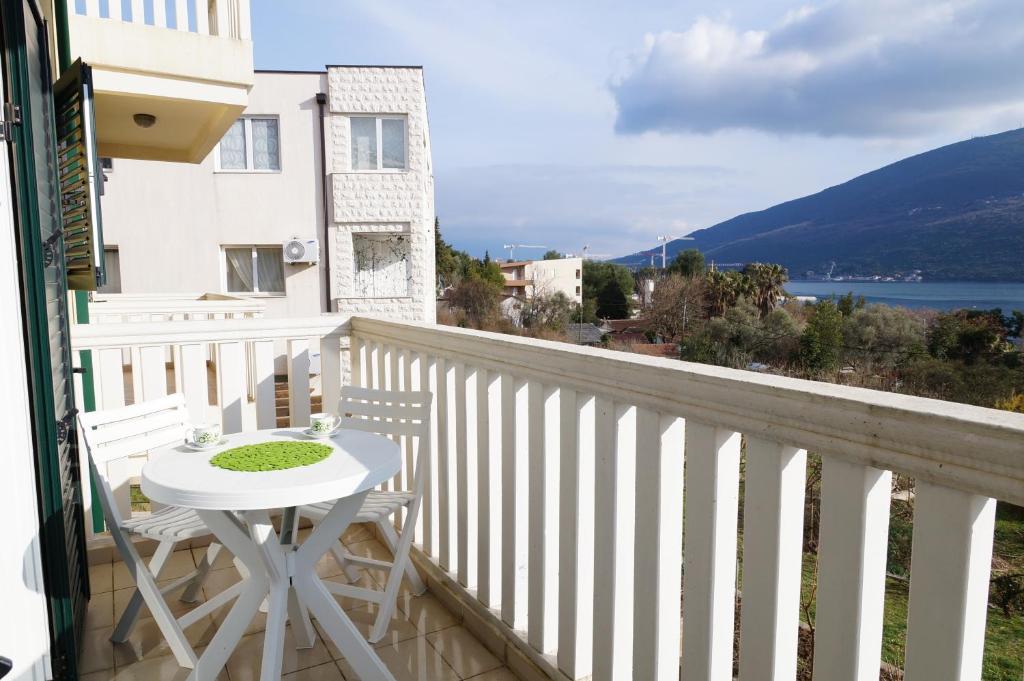 uma varanda com mesa e cadeiras e vista para a água em Apartment Begonia of Kumbor em Herceg Novi