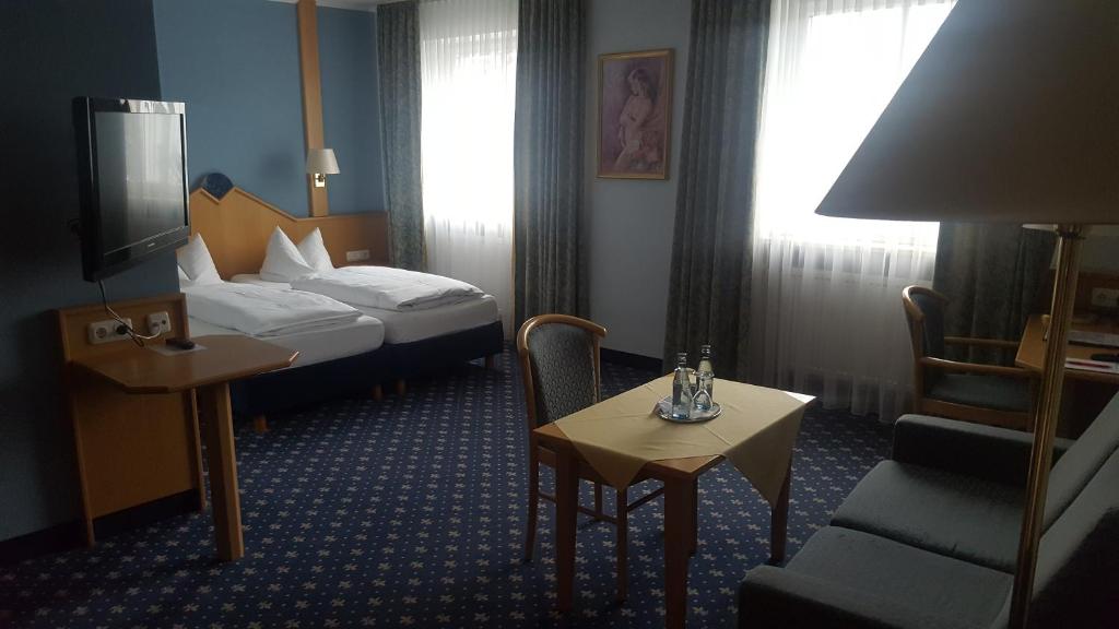 Habitación de hotel con cama, mesa y TV. en Hotel-Cafe Rathaus en Bad Abbach